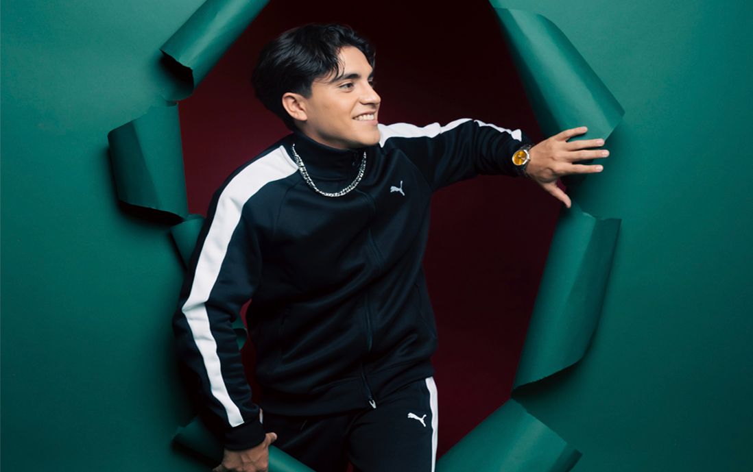 Hombre usando lanzamiento de conjunto de Puma en color verde oscuro con franja y logo de color blanco.